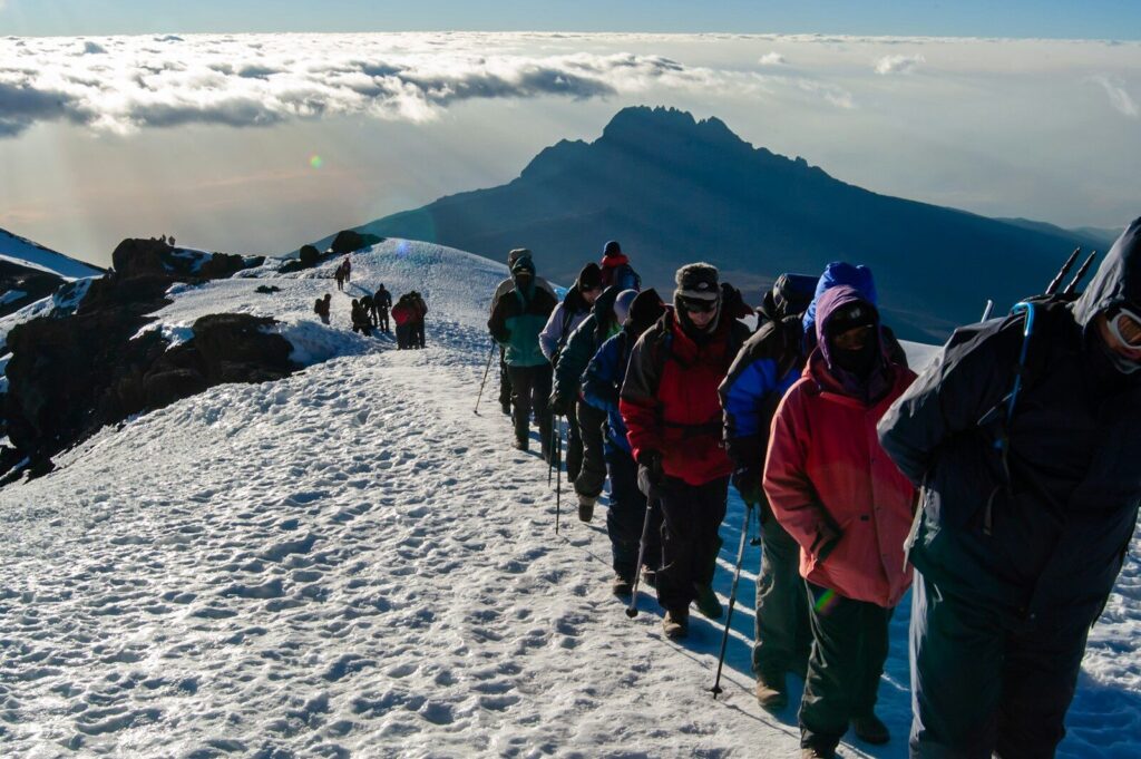 people in blue and red jacket standing on snow covered ground during daytime